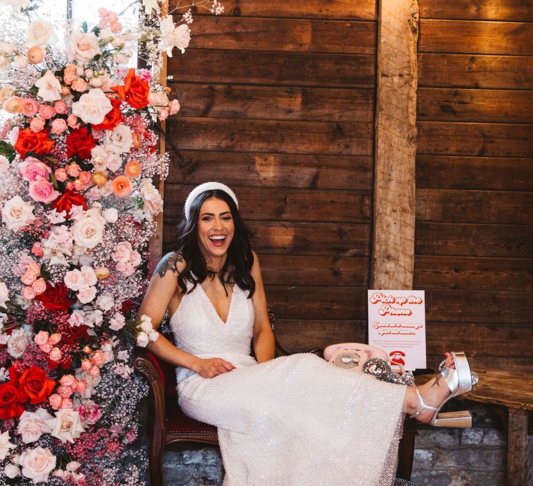 Bride in sparkly wedding dress with disco ball decor, silver chunky platform wedding shoes and colourful pink flower decorations 