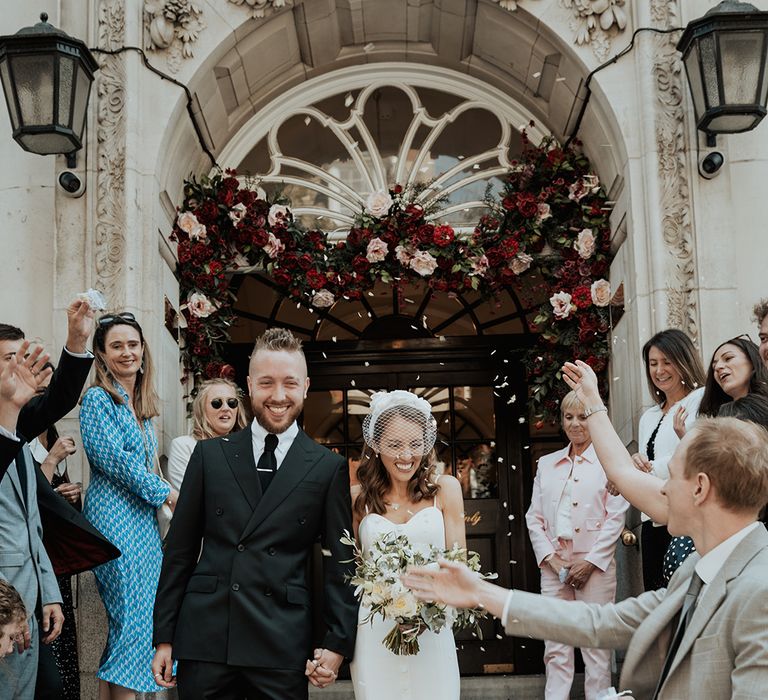 confetti moment on the steps of Chelsea Town Hall with groom in a black suit and bride in separates 