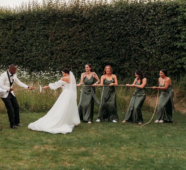 Bridal party and groomsmen play tug of war at Crumplebury wedding venue