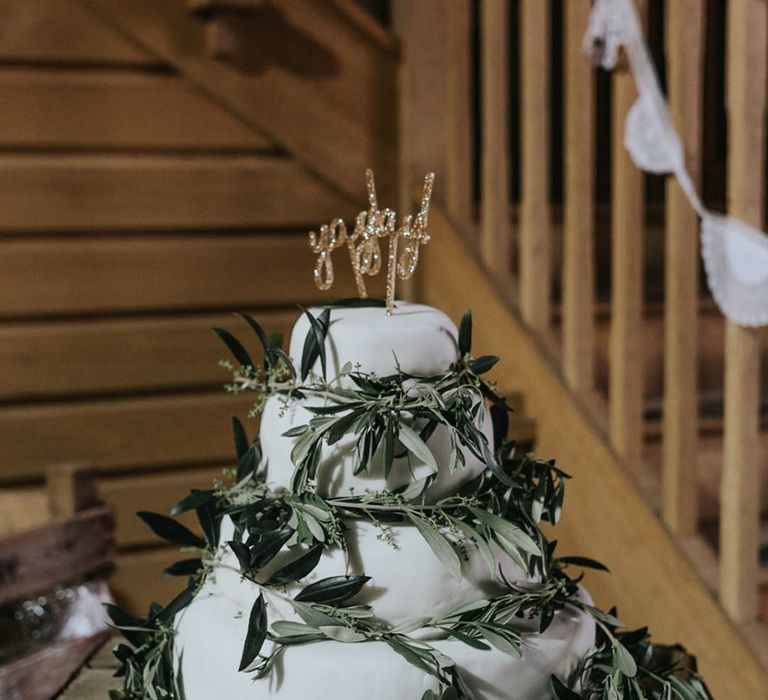 Four tier small wedding cake with white icing and green foliage 