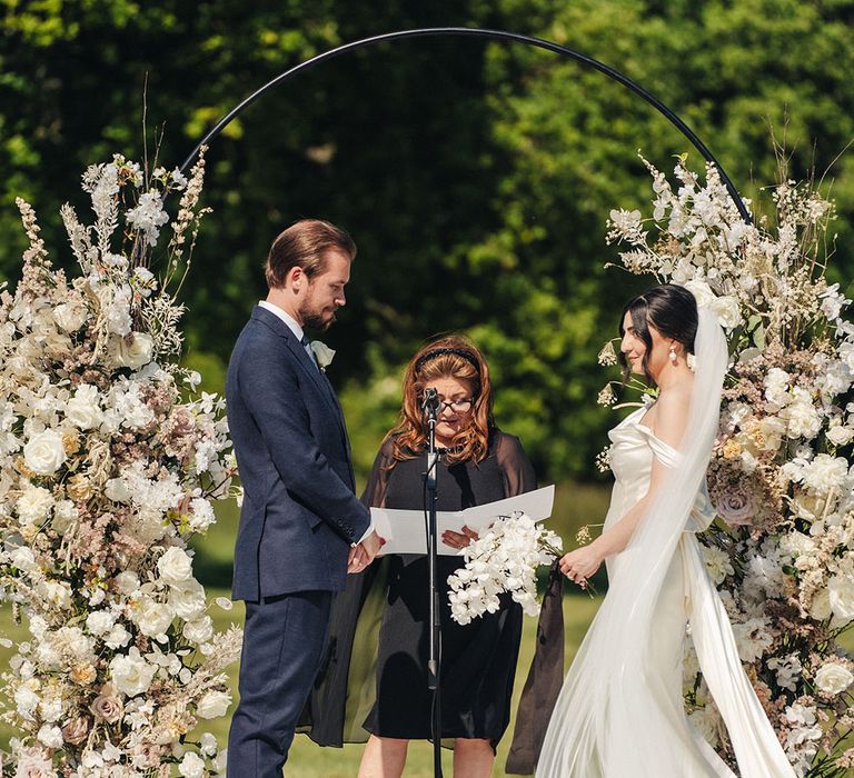 Bride and groom at their outdoor wedding ceremony with white flower columns