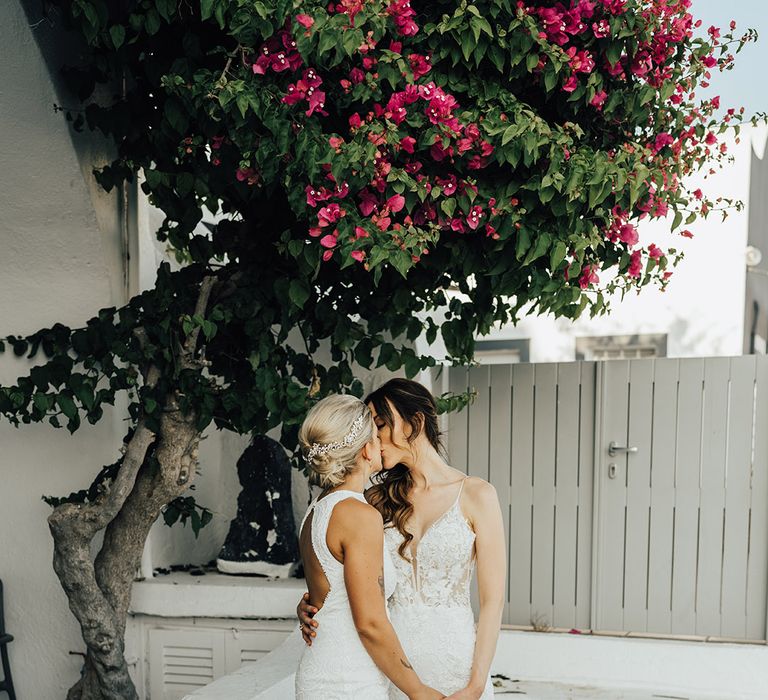 Brides share a kiss at their same sex wedding in boho lace gowns for intimate destination wedding 