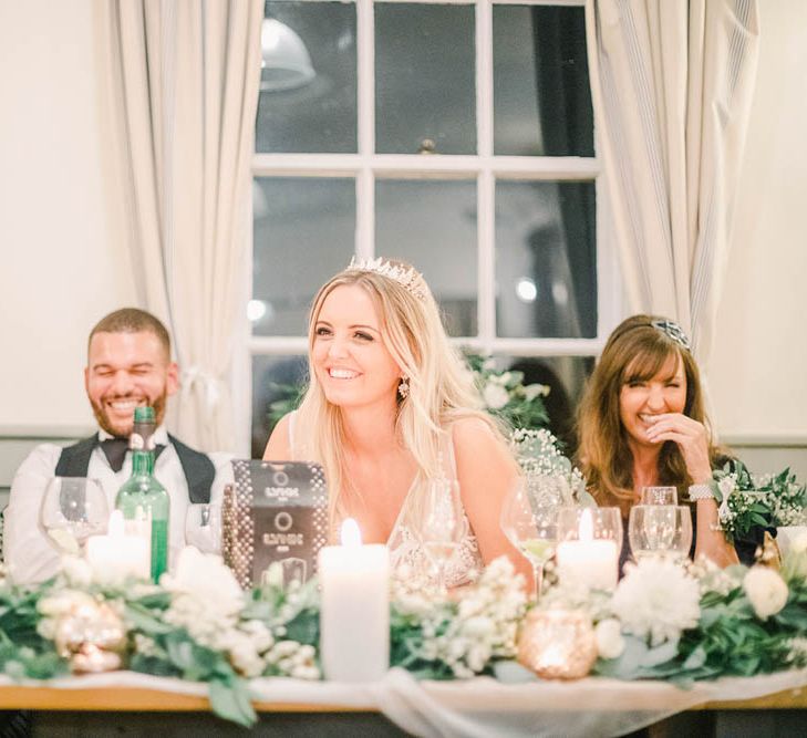 Bride and groom smiling during the speeches at their black tie winter wedding