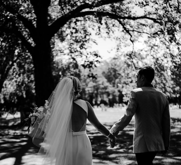 black and white portrait of bride and groom holding hands 