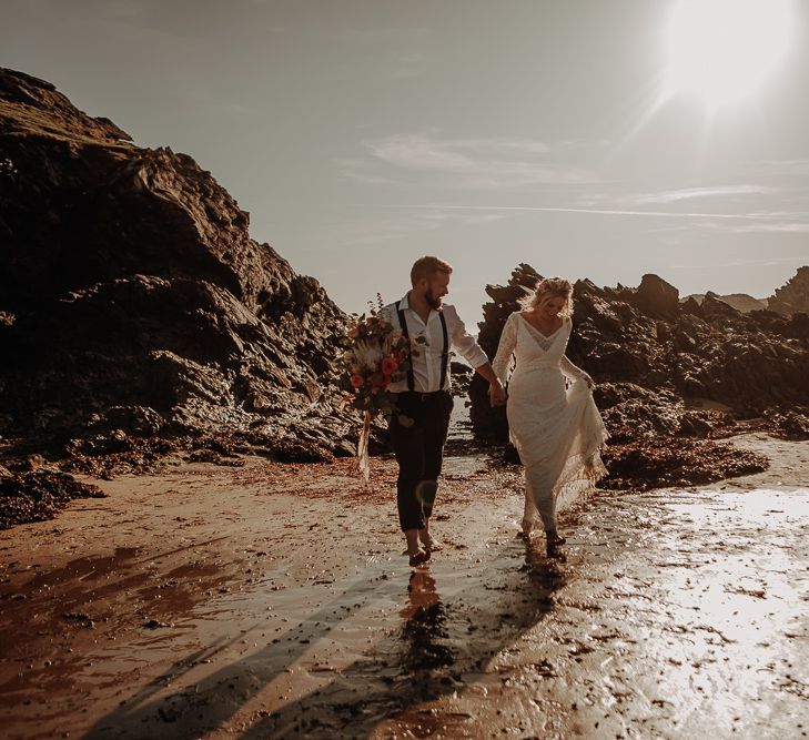 Bride and groom walk barefoot on the beach at Anglesey Island