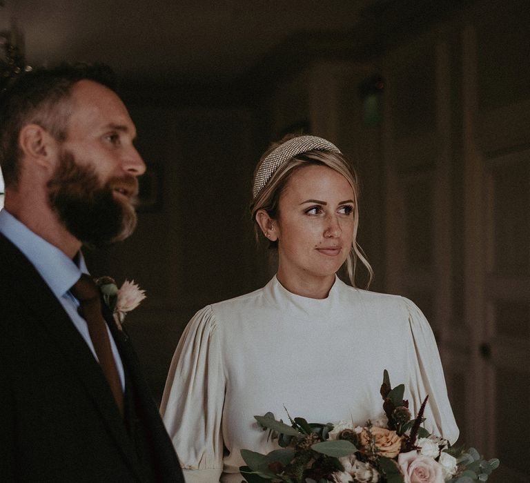 Bride in high neck wedding dress and headband at the wedding ceremony 