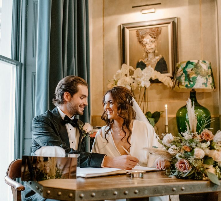 Bride and groom signing their wedding contracts bride looking lovingly at her husband