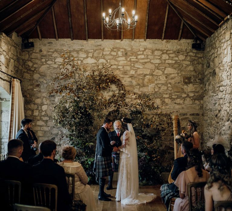 Bride and groom getting married in bespoke ceremony in Kirknewton House Stables