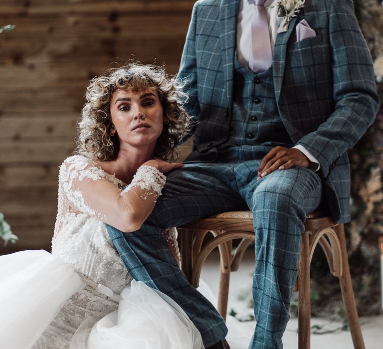 Bride with short curly wedding hair leans on Groom's knee