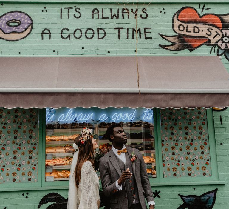 Couple stand in front of doughnut stand holding balloons, sign reads "It's always a good time"