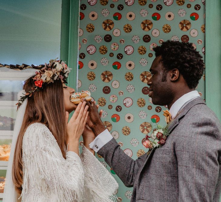 Groom feeds bride doughnut outside doughnut stand