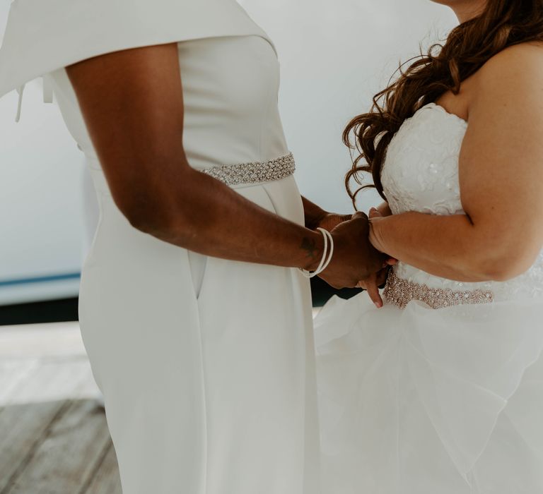 Black bride and biracial bride holding hands at same sex wedding 