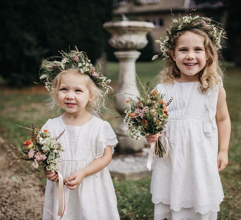 Cute flower girls in white dresses and wildflower wedding crowns 