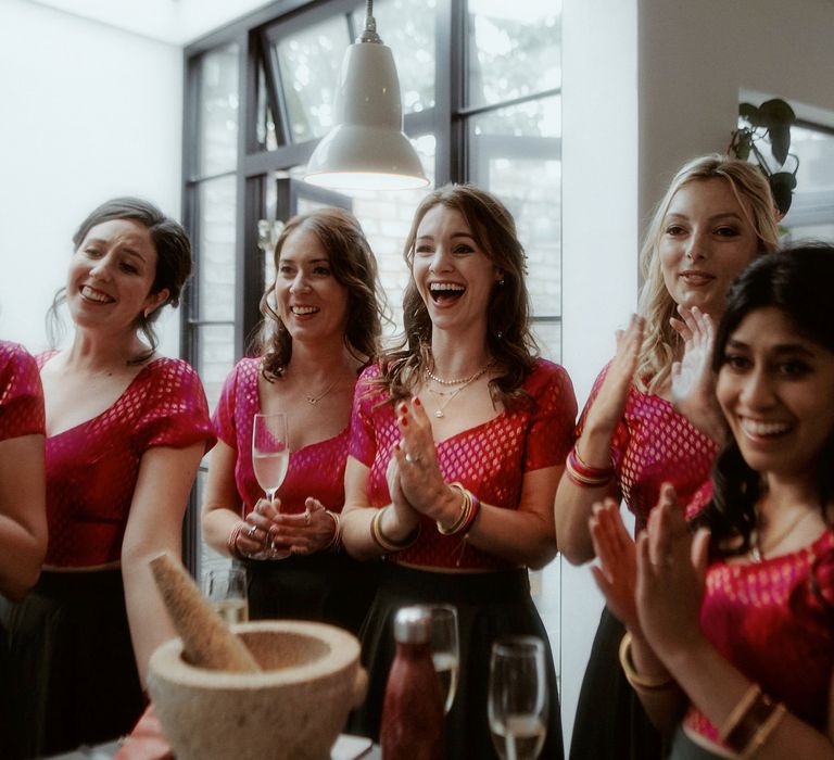 Bridesmaids in pink and green lenghas clapping on the wedding morning 