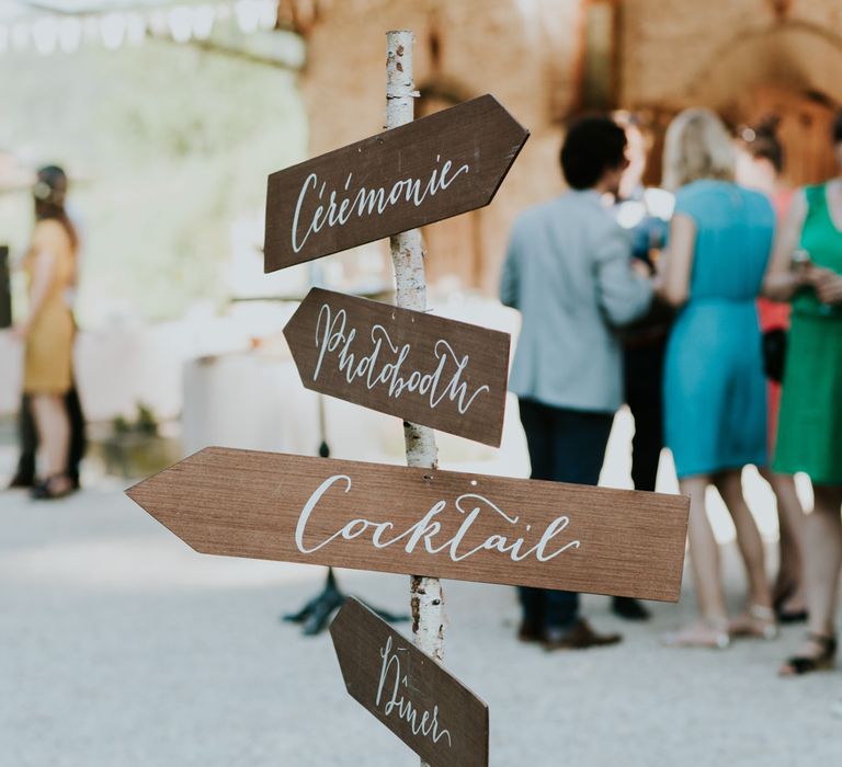 Wooden French wedding signage that gives direction to the ceremony, photo booth, cocktails and dinner.