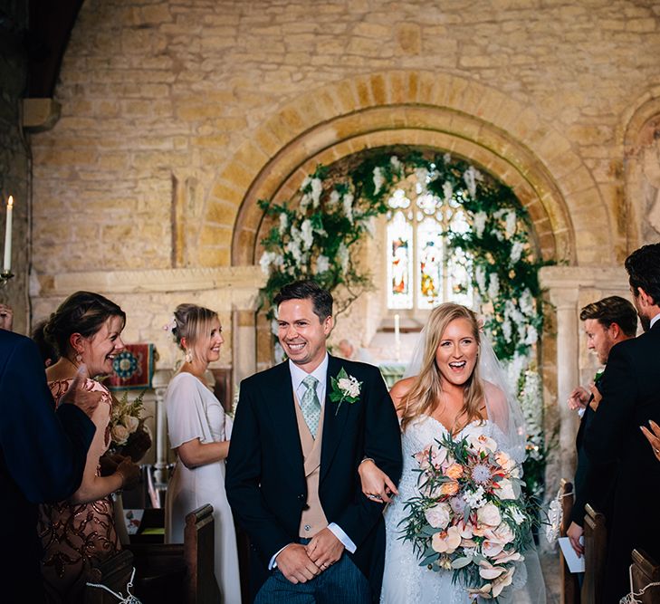 Bride and groom walking down the aisle laughing at Church wedding 