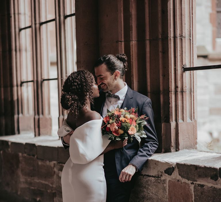 Bride & groom kiss near window after wedding ceremony