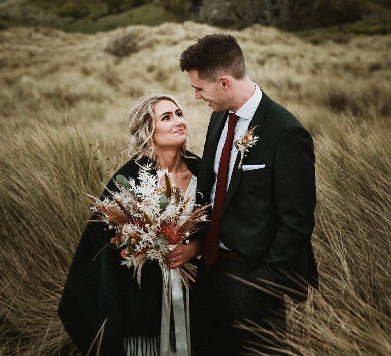 Bride & groom look lovingly at one another on the day of their wedding whilst stood outdoors