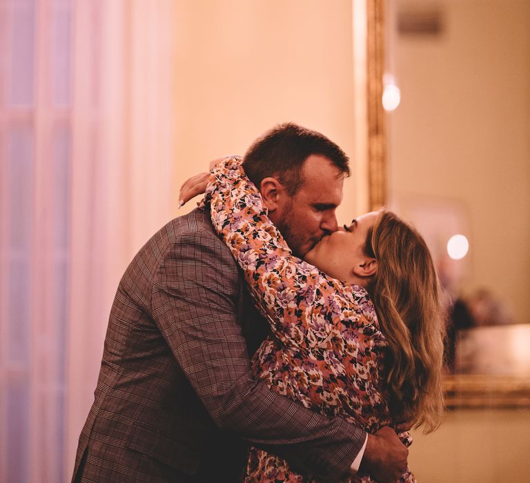 Bride wraps her arms around groom as they kiss on wedding day