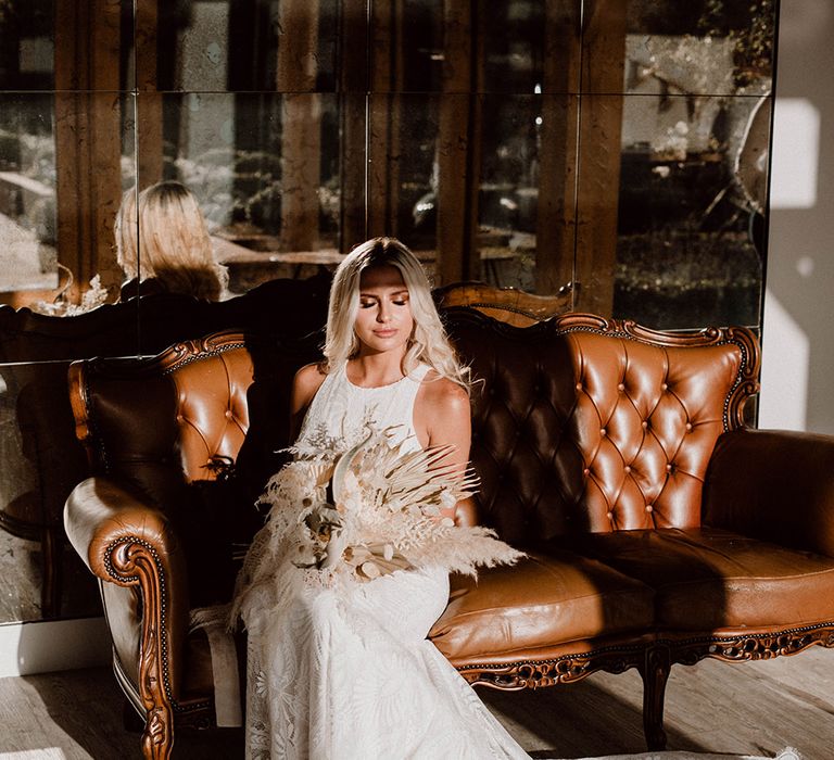 Bride sitting on a leather sofas with light flooding through the windows at Pryors Hayes wedding venue 