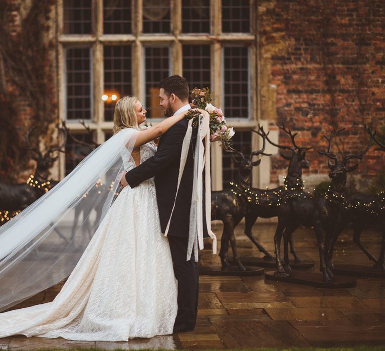 Bride in a princess wedding dress with bespoke cape holding a blush bouquet tied with lots of ribbon 