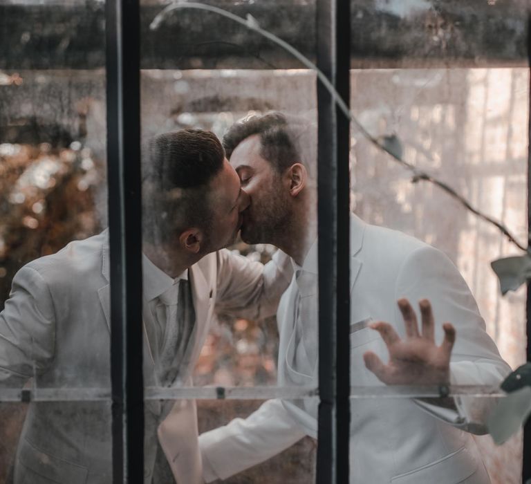 Grooms kiss in glasshouse