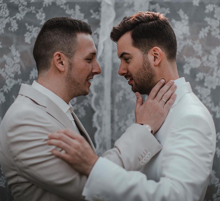 Grooms embrace in light grey wedding suit