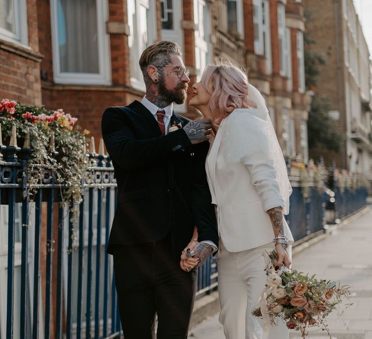 Couple hold hands in street and lean in for a kiss