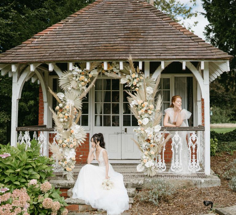 Two brides at Berwick Lodge with neutral colour flower arch for boho inspired wedding shoot