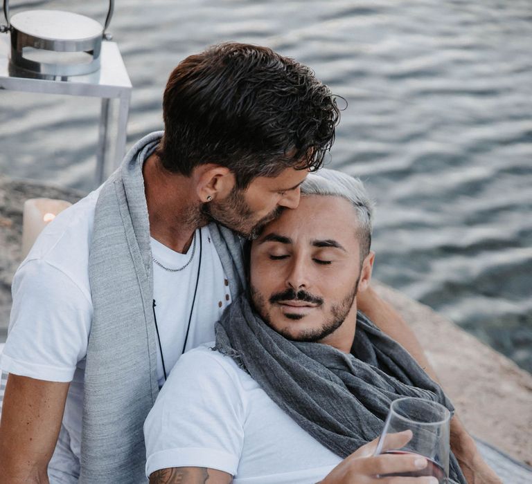 Groom leans back into boyfriend as they laugh together 