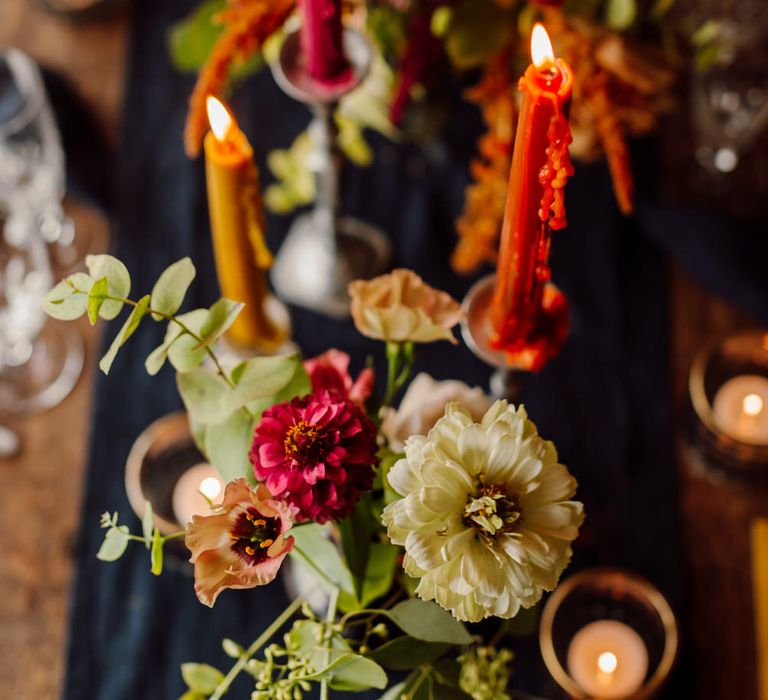 Pink, orange and yellow tapered candles with dahlias and wild roses