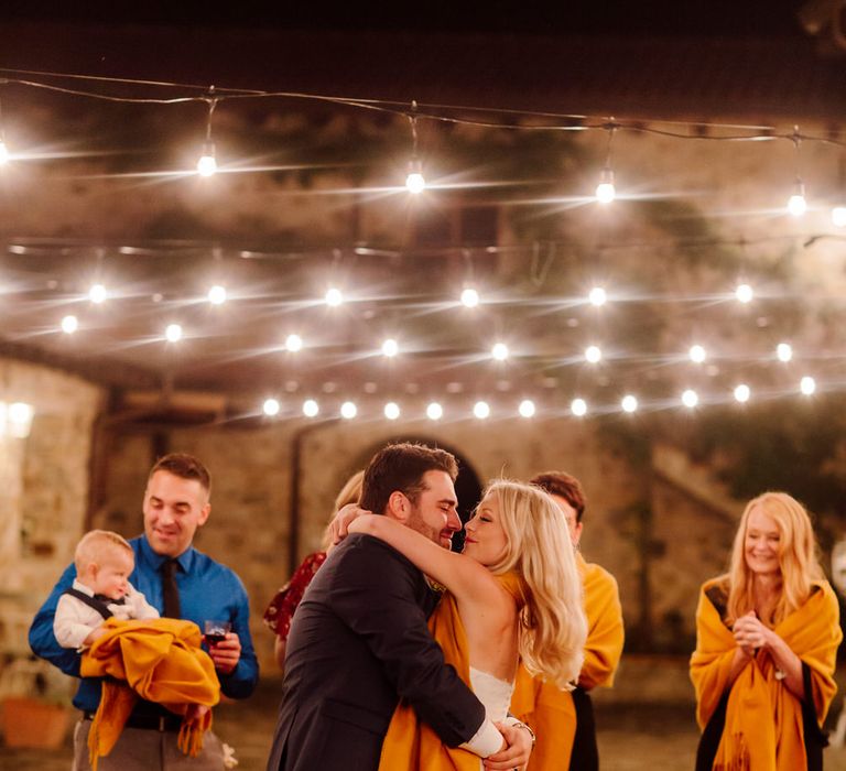 The guests circling the bride and groom as they dance, smiling and clapping