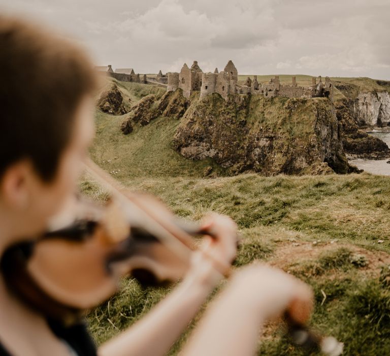 Violinist plays at clifftop wedding overlooking Dunluce Castle