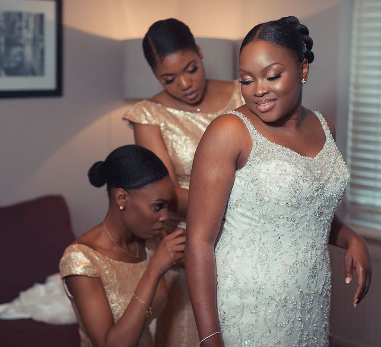 Bride has her dress done up br bridesmaids on her wedding day