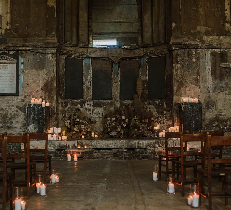 The altar at The Asylum wedding venue decorated with pillar candles and dried and fresh wedding flower arrangements 