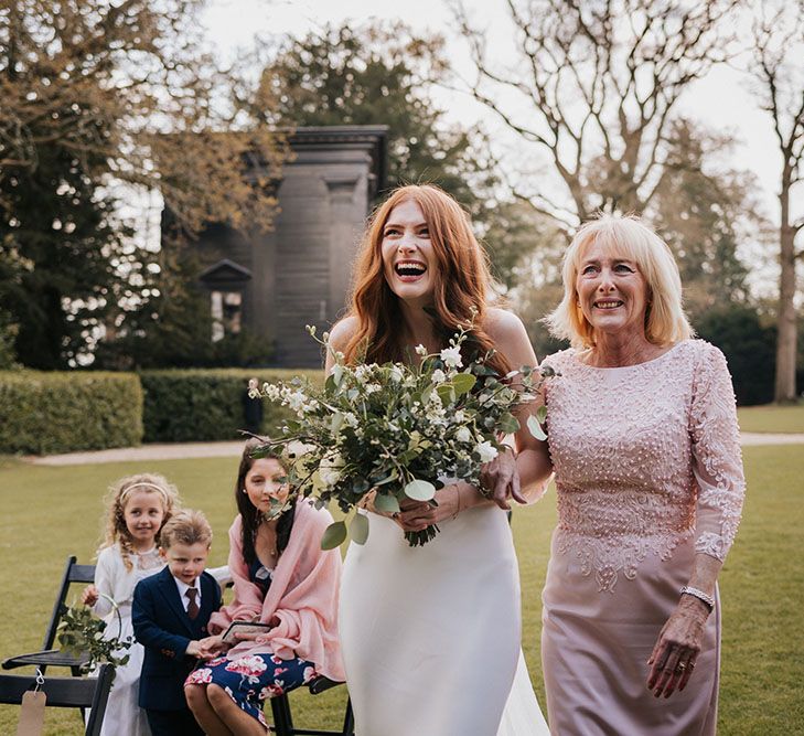 Mother of the bride in a pink dress walking her daughter down the aisle at The Larmer Tree Gardens 