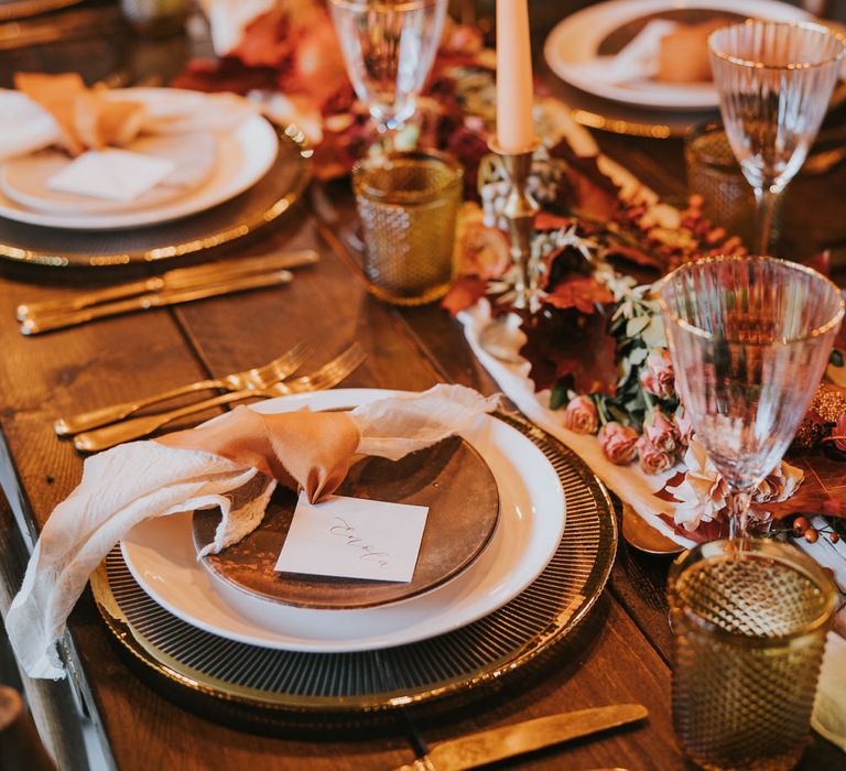 Rustic, vintage tablescape in rust and orange tones with flat foliage centrepiece decoration