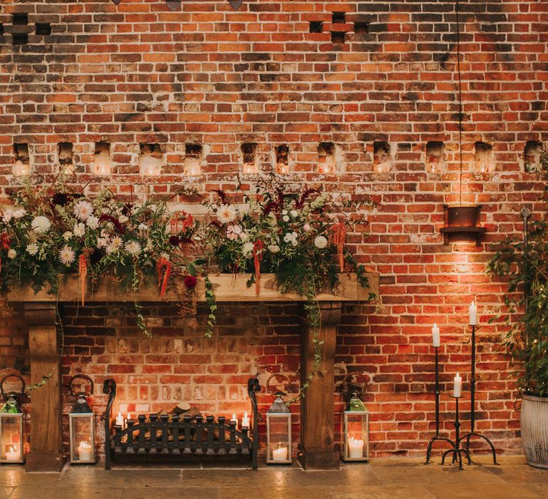 Fireplace at Hazel Gap Barn decorated in red, white and green foliage floral arrangement 