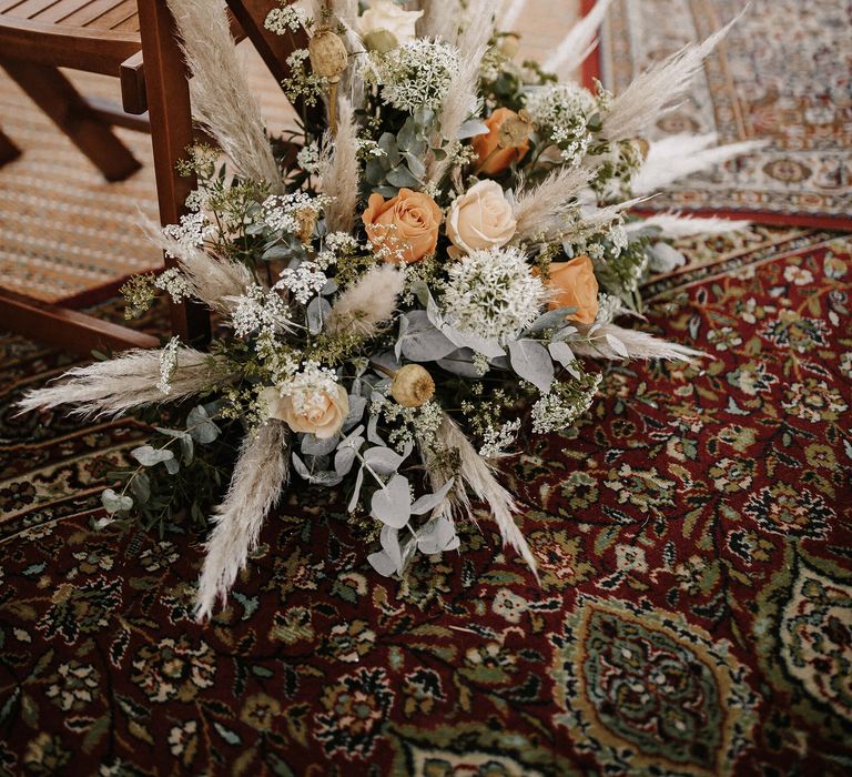 Wedding ceremony aisle flowers with dried grasses, foliage and roses 