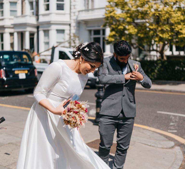 Bride & groom walk with one another through Chelsea as the sun shines on their wedding day