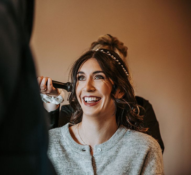 Bride on the wedding morning having her hair and makeup done whilst wearing a jewel headdress 