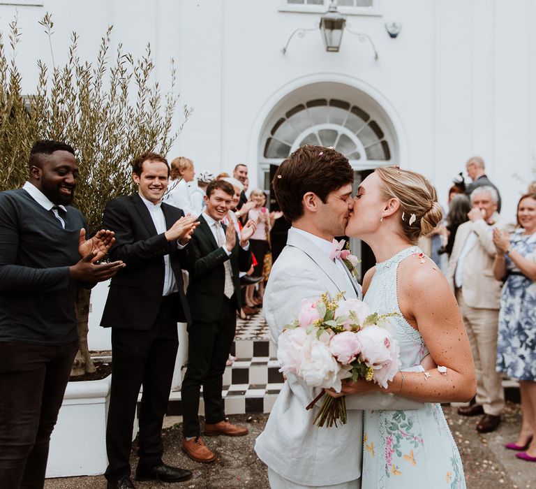 Bride & groom kiss outside the Belair House as wedding party watches and throw confetti around them