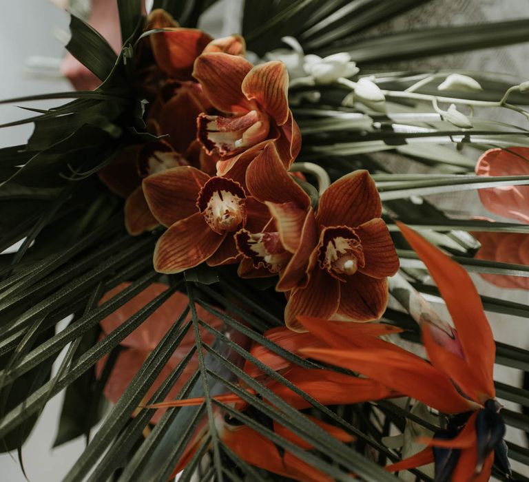 Tropical bridal bouquet with burnt orange flowers and palm leaves for birds of paradise wedding inspiration