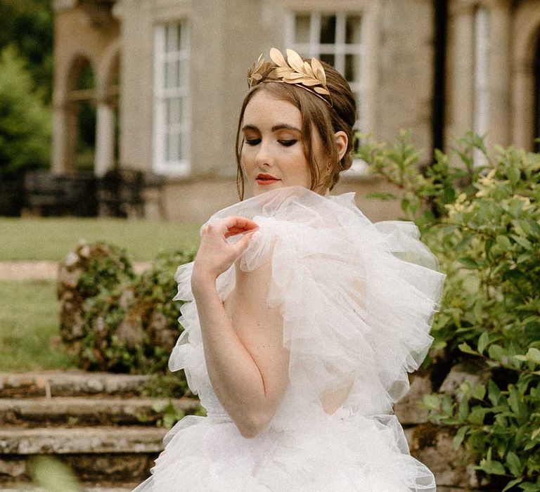 Bride in a tulle wedding dress with brown eyeshadow and black eyeliner wearing a gold crown 