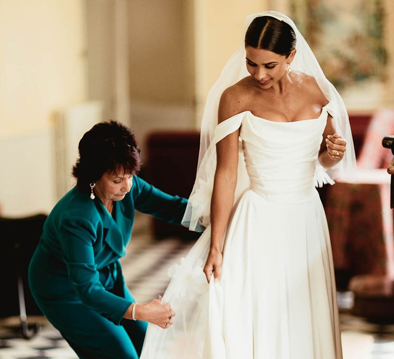 Mother of the bride helps bride with her gown on her wedding day