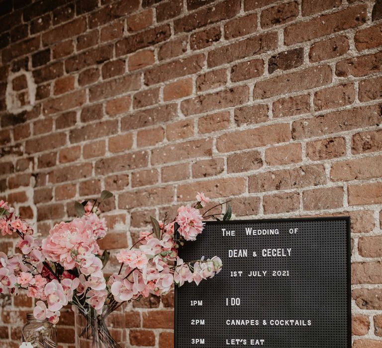 Order Of The Day on black board next to pink florals