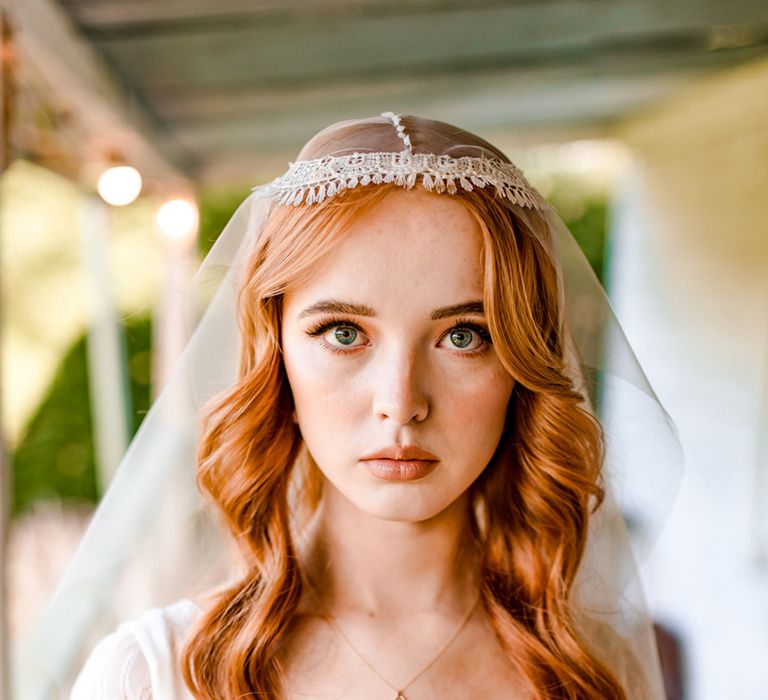 Bride with long curled hair and Juliet cap wedding veil wearing v neck wedding dress holds colourful bridal bouquet