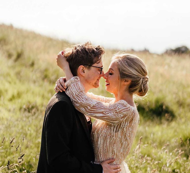 Bride & groom wrap their arms around one another 