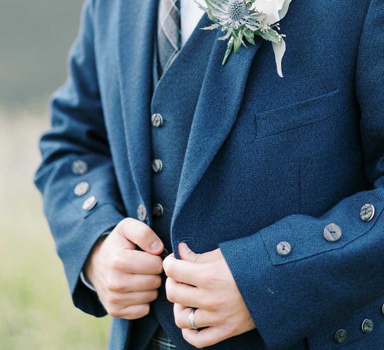 groom in a blue wool waistcoat and jacket with white rose buttonhole flower 