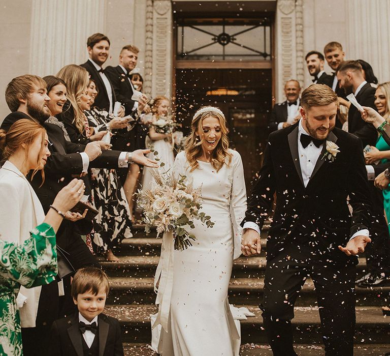 Confetti moment on the steps at Old Marylebone Town Hall with bride in a Pronovias wedding dress and groom in a black-tie suit